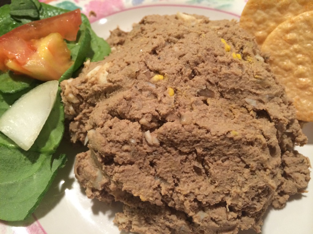close up image of chopped liver with crackers and condiments.
